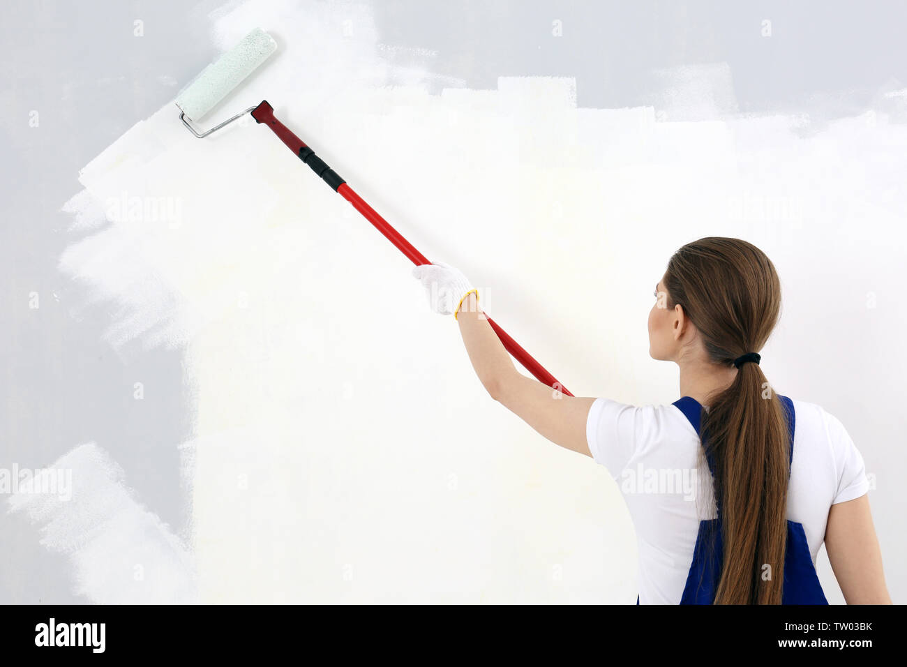 Beautiful young woman painting wall in room Stock Photo - Alamy