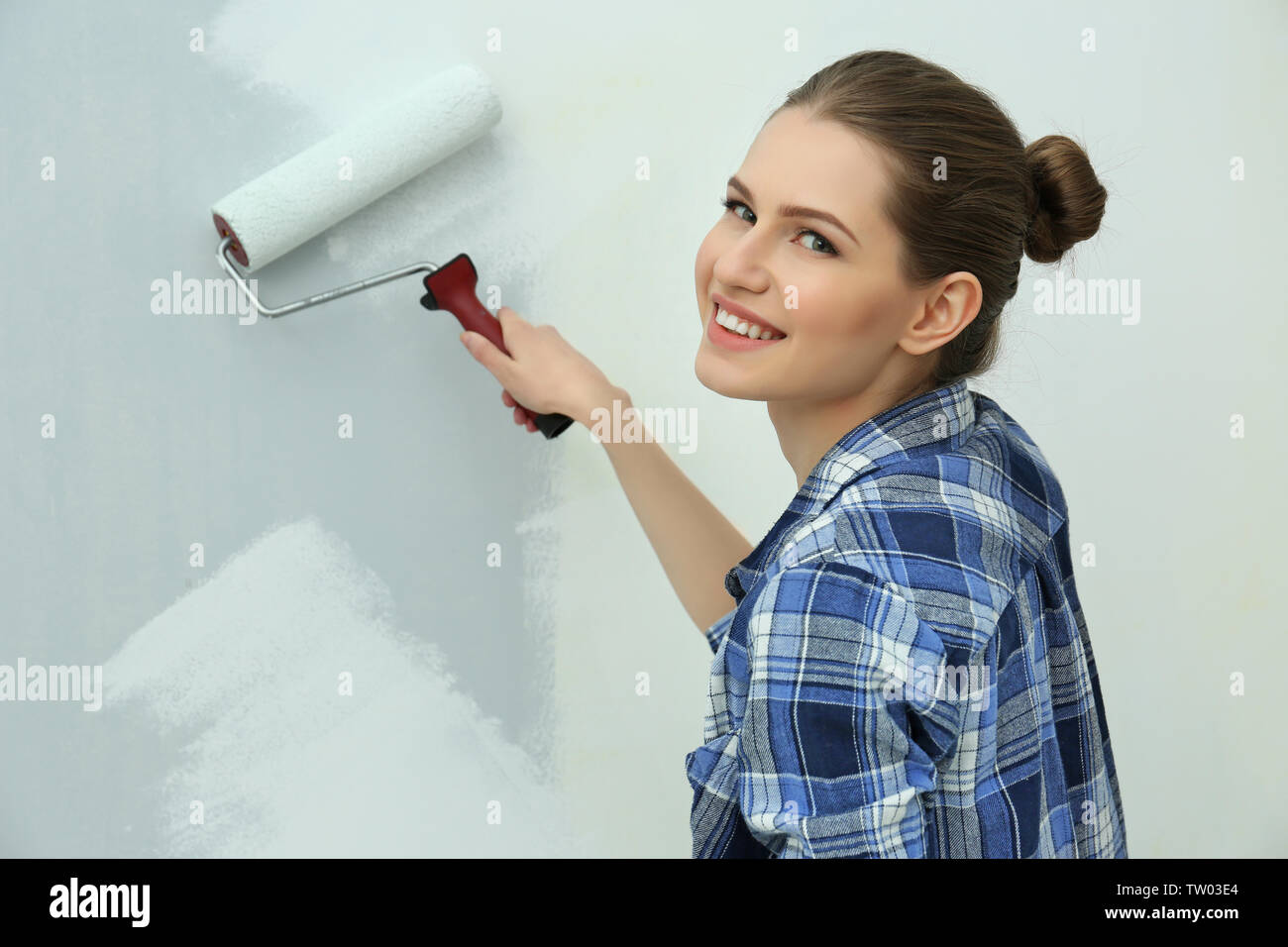 Beautiful young woman painting wall in room Stock Photo - Alamy