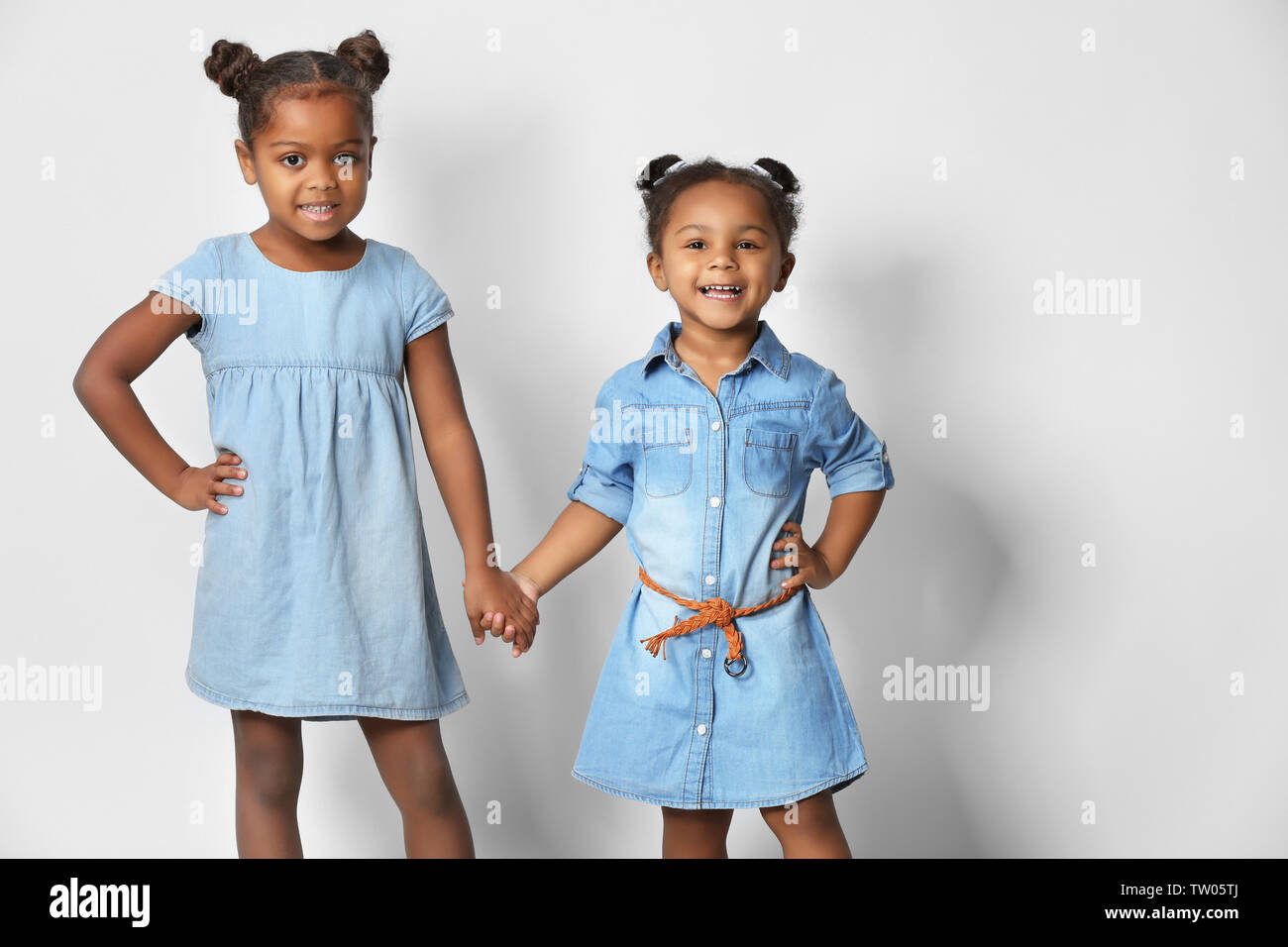 Two cute African girls holding hands on white background Stock Photo