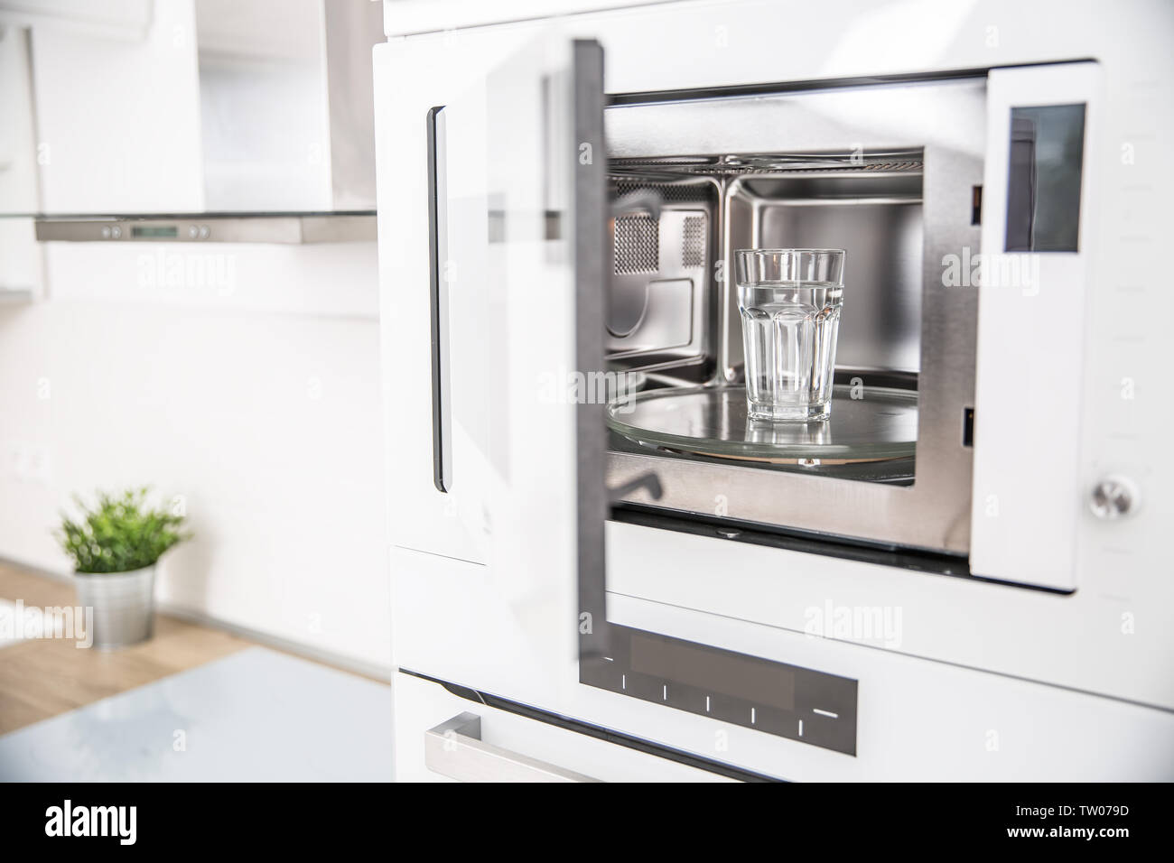 Builtin microwave oven in the kitchen with a cup of pure water Stock