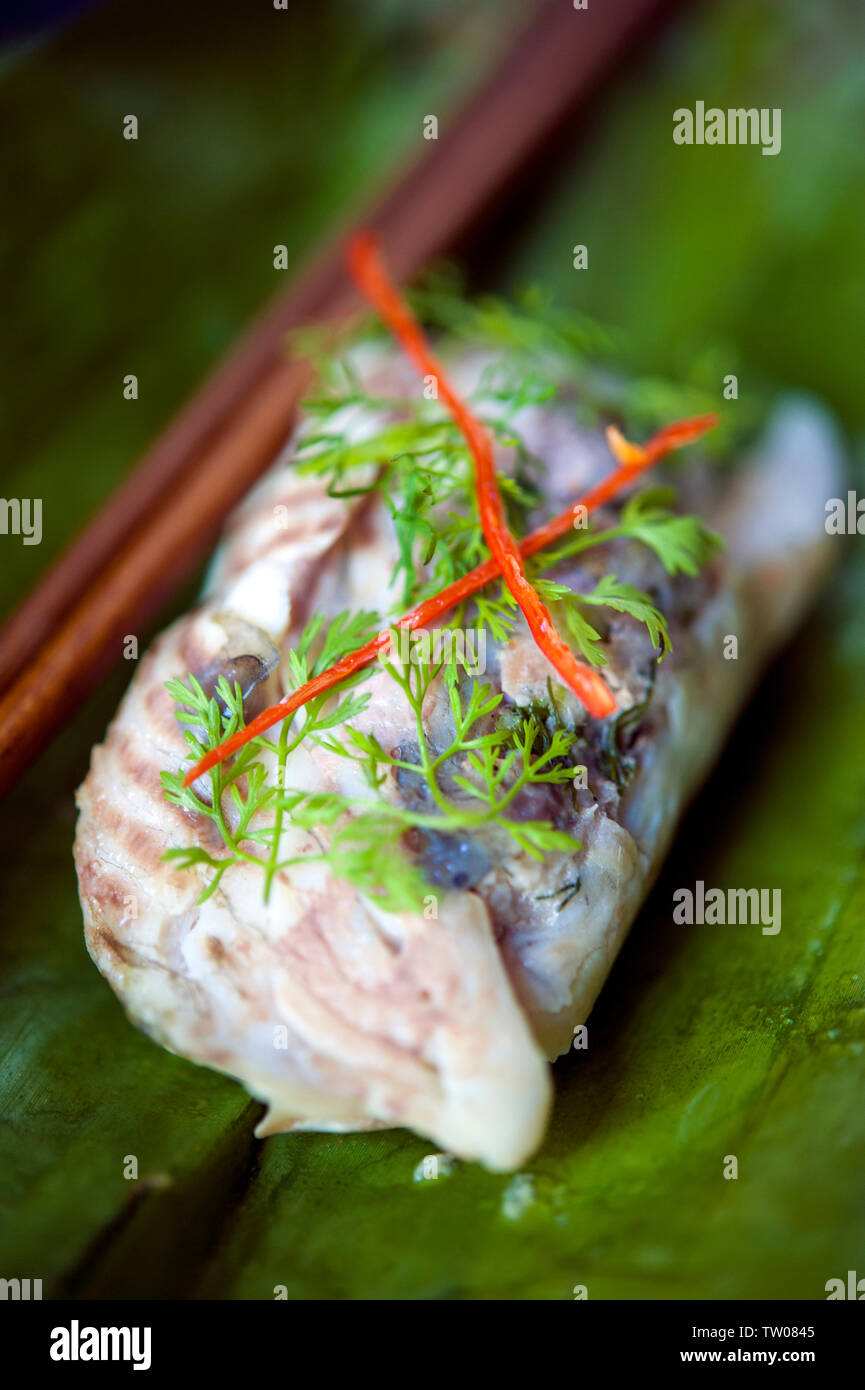 Grilled fish and pork wrapped in banana leave at 3 Nagas Restaurant. Luang Prabang, Laos PDR. Stock Photo