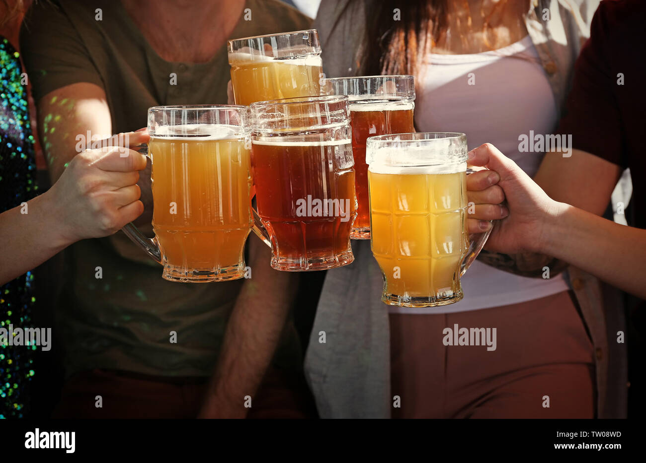 People clinking mugs with beer in pub, closeup Stock Photo