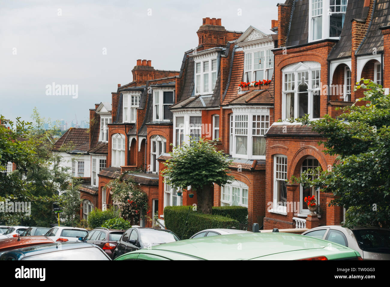 Looking down the peaceful terrace-housed streets of Muswell Hill, North London, on a muggy summer's morning. London skyline is visible behind Stock Photo
