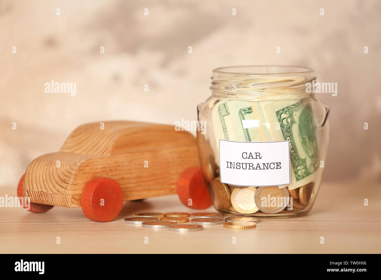 Glass jar with money and wooden car toy on table Stock Photo