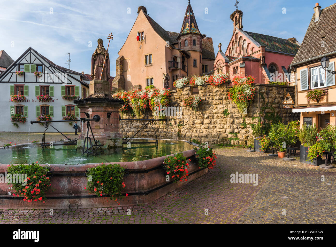 picturesque place in the old village Eguisheim, Alsace, France, scenic square with castle Château de Saint-Léon-Pfalz and well Stock Photo
