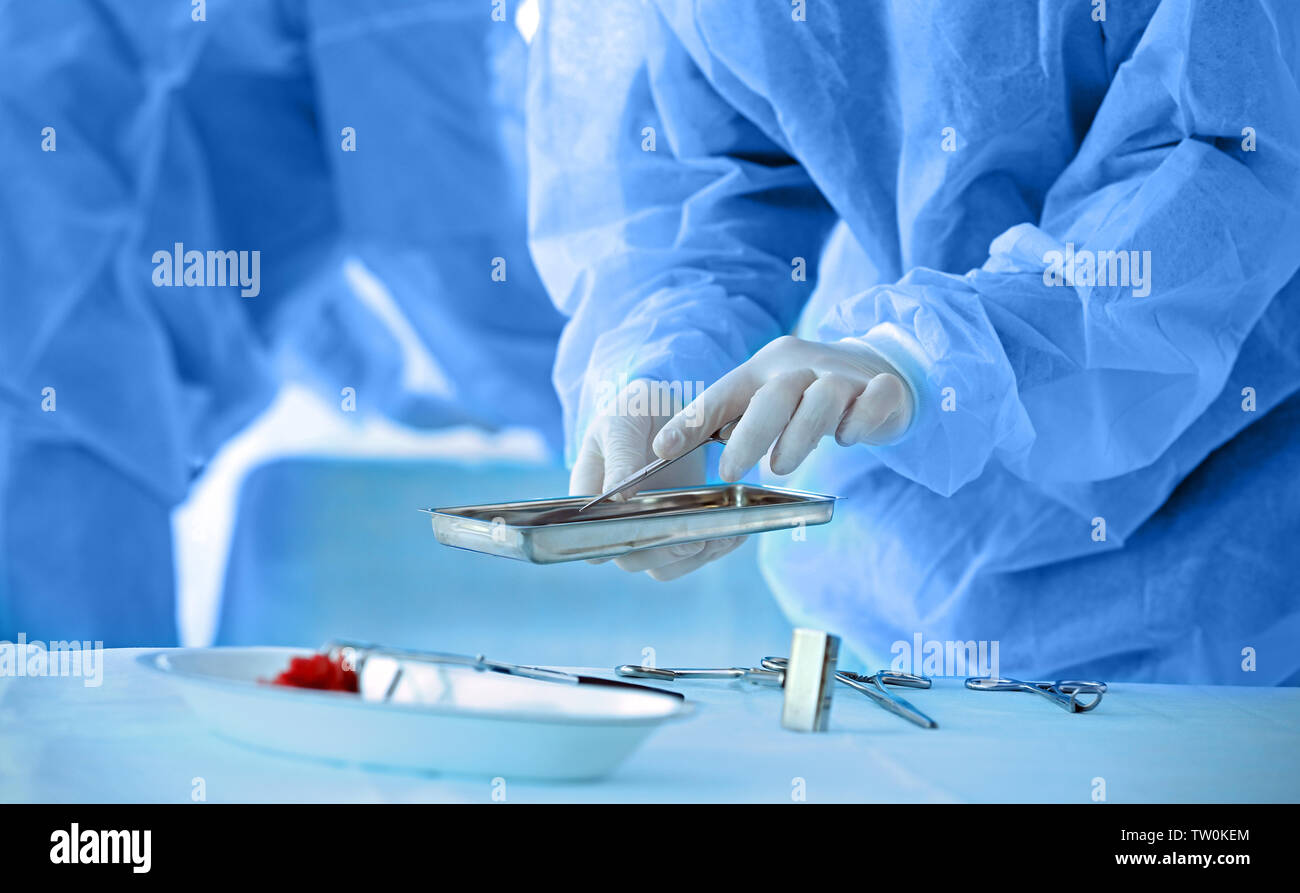 Hands of doctor taking instruments for surgical operation in clinic ...