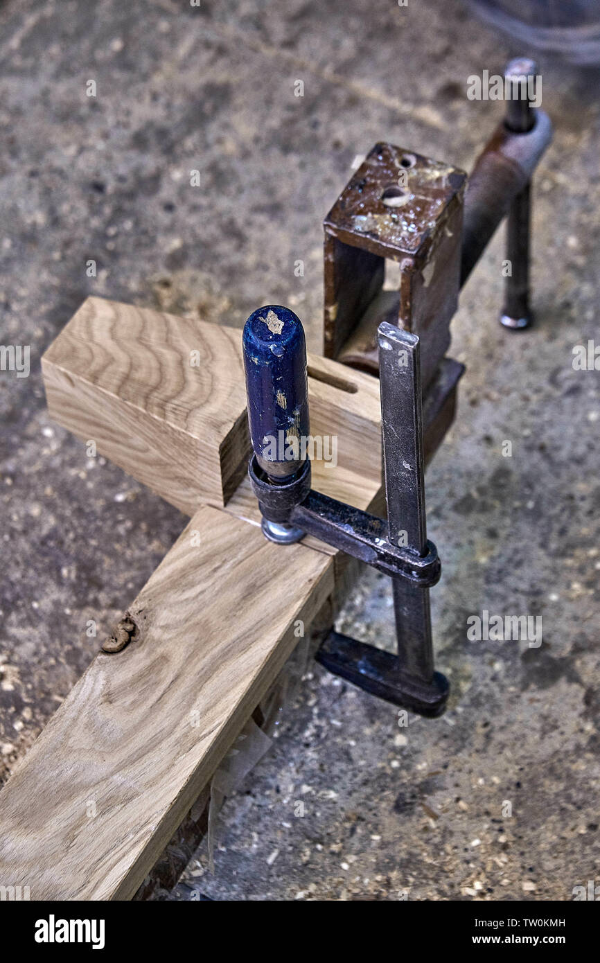 Furniture legs from solid oak. Closeup. Metal clamps tightening wooden