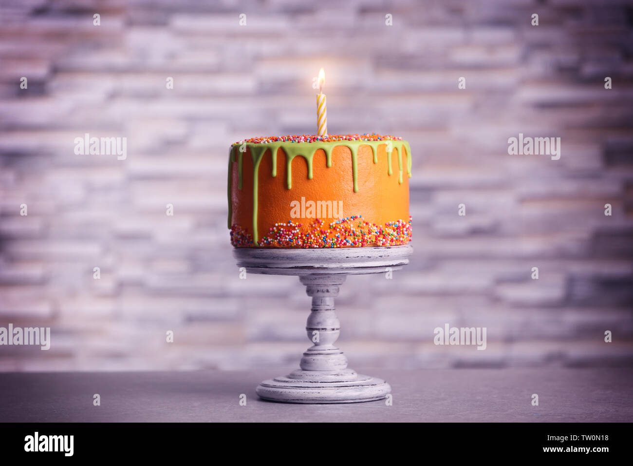 Birthday cake with one candle on blurred background Stock Photo - Alamy