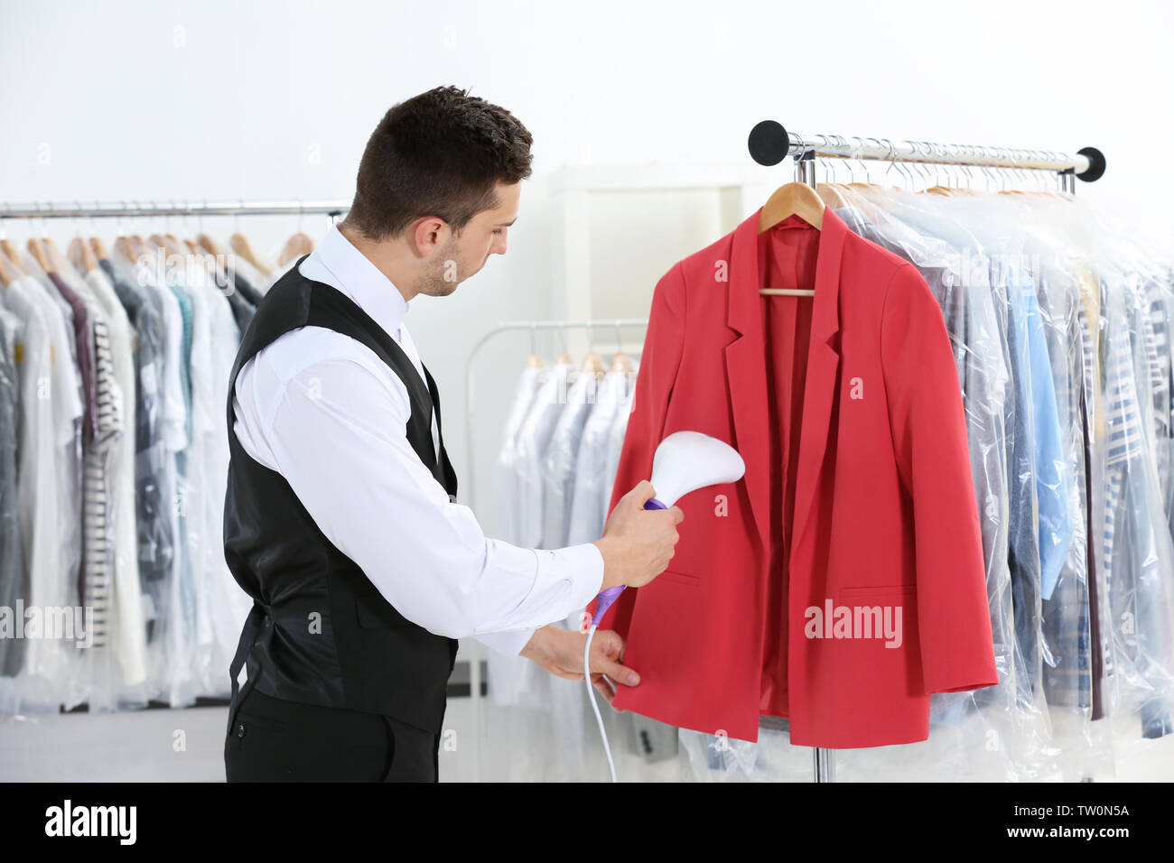 Man with steamer cleaning clothes in drycleaning salon Stock Photo Alamy
