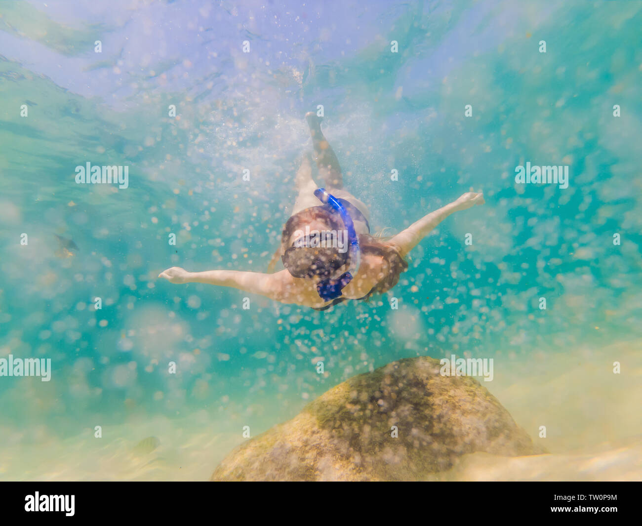 Happy woman in snorkeling mask dive underwater with tropical fishes in