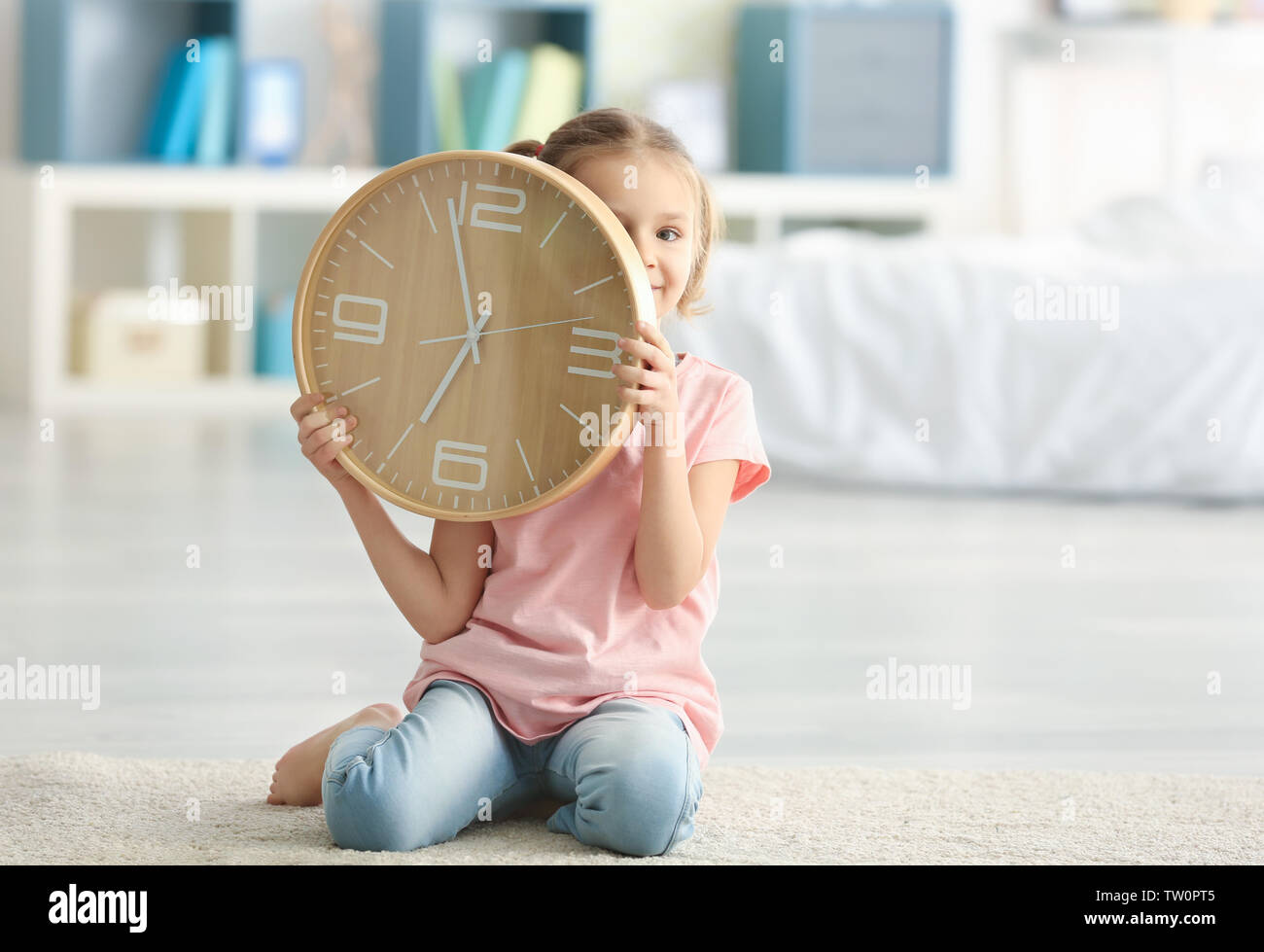 Cute little girl with big clock sitting on floor at home Stock Photo ...