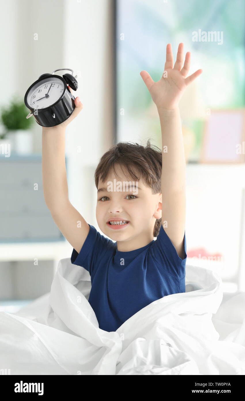 Cute little boy with alarm clock in bed Stock Photo Alamy