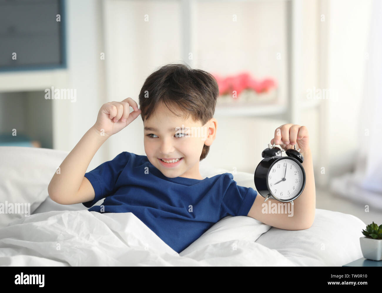 Cute little boy with alarm clock in bed Stock Photo Alamy