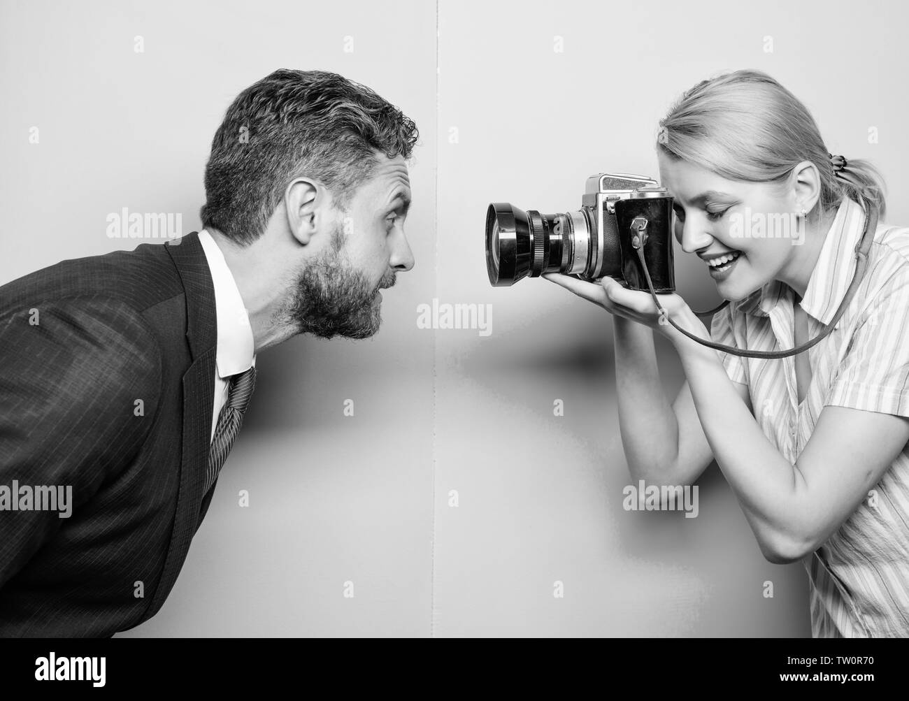 Enjoying photo shoot session. Photographer shooting male model in studio. Pretty woman using professional camera. Businessman posing in front of female photographer. Fashion shooting in photo studio. Stock Photo