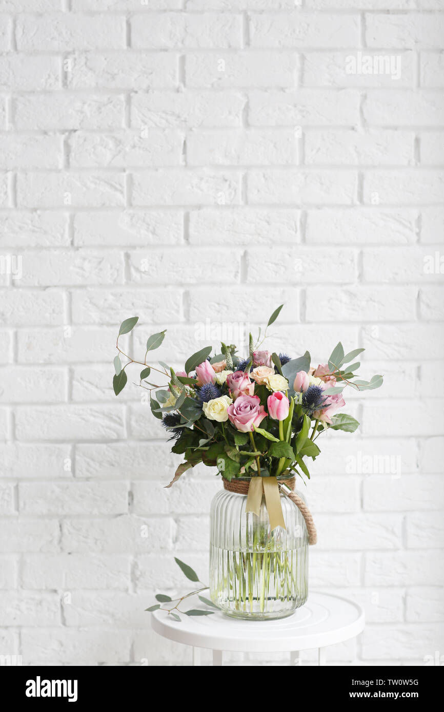 Glass vase with beautiful bouquet on brick wall background Stock Photo