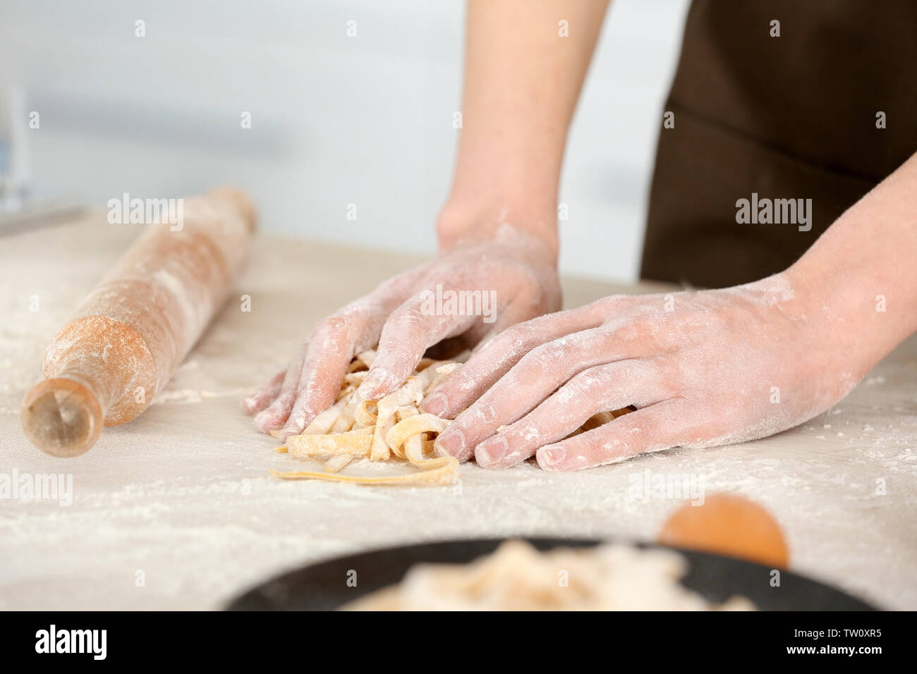 Woman preparing pasta on kitchen table, closeup Stock Photo