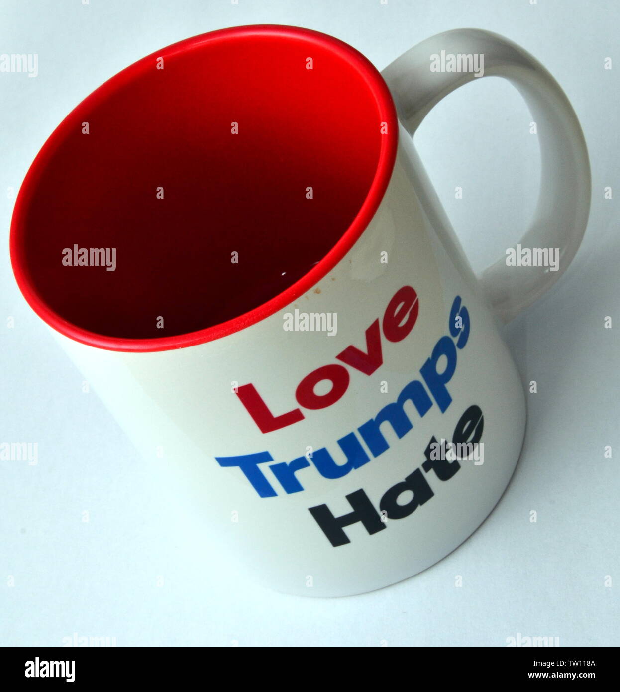 A studio shot of a mug with a white exterior and a red interior with a 'Love Trumps Hate' message on the outside, taken on a white background Stock Photo
