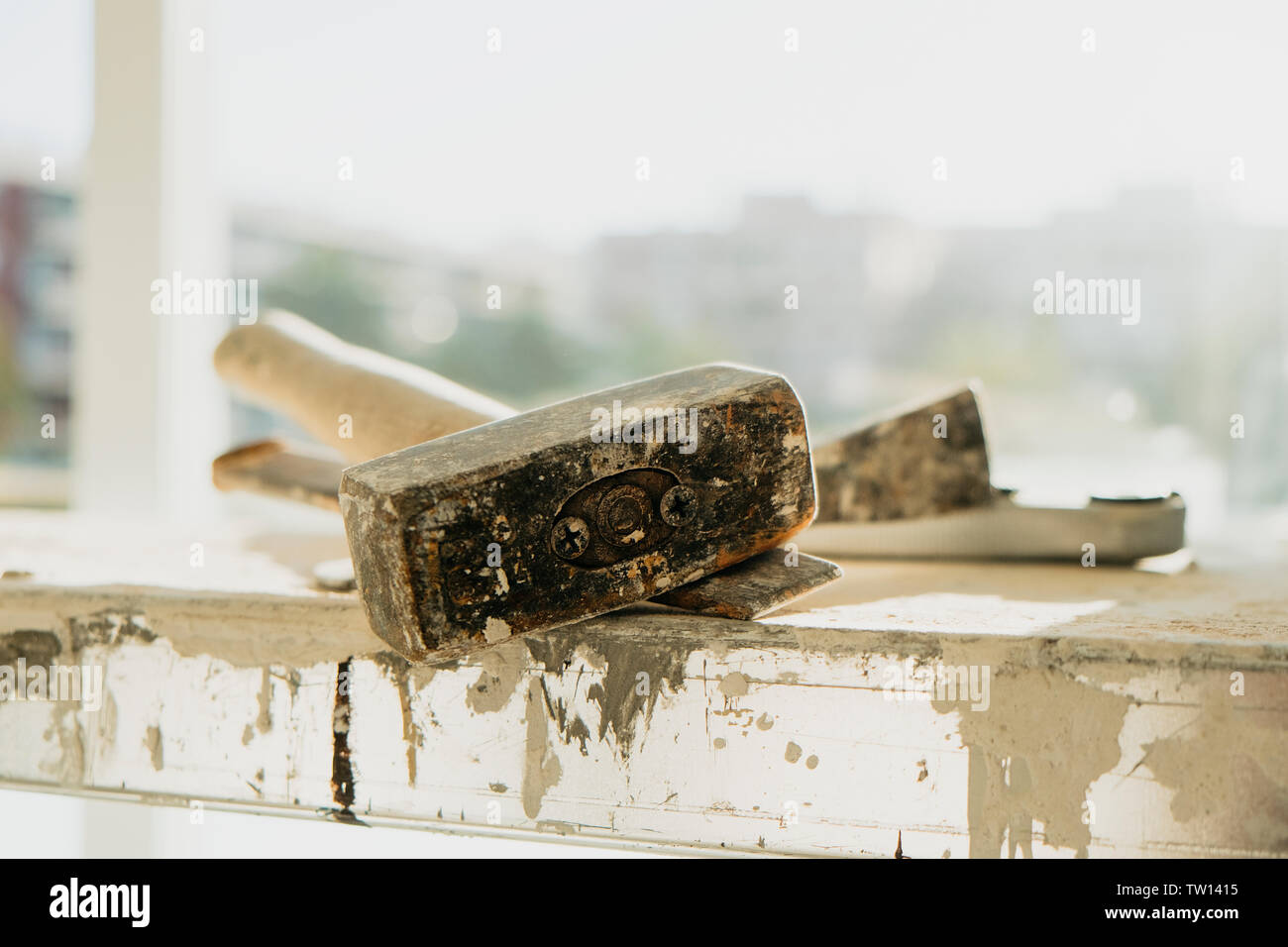 closeup of a rusty metal mallet and a cold chisel, on a working platform stained with paint and plaster, in a building Stock Photo
