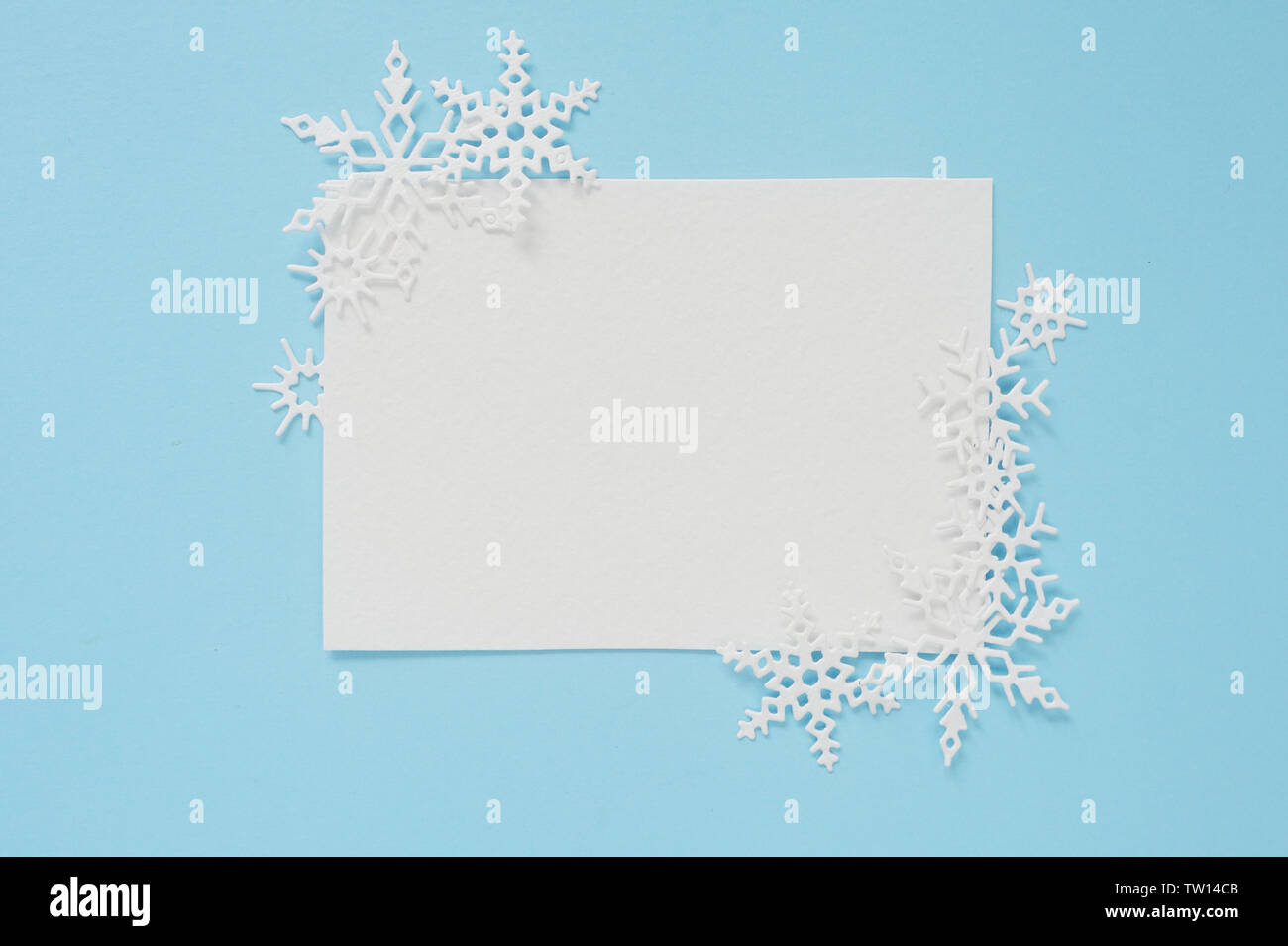 Christmas or winter composition. Frame of white snowflakes and white sheep of paper on pastel blue background. Christmas winter, new year concept Stock Photo