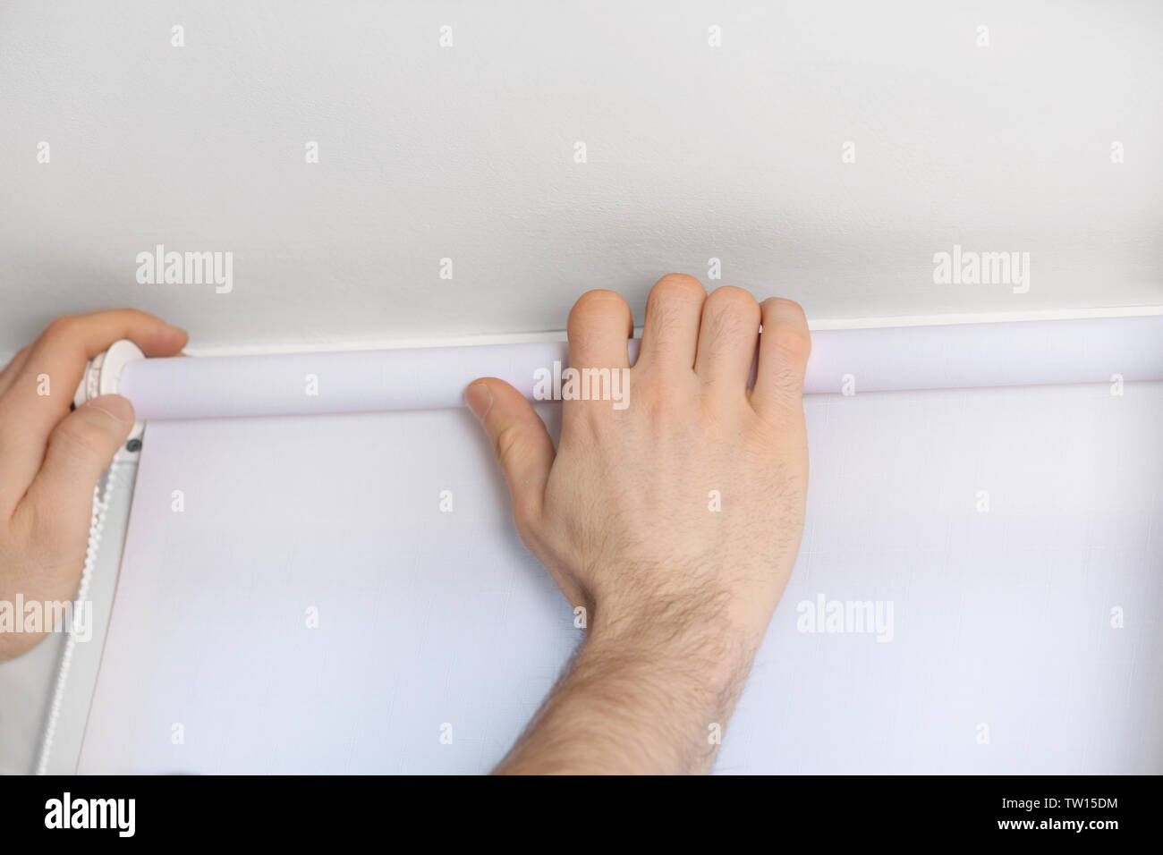 Male hands installing roller blinds on window Stock Photo