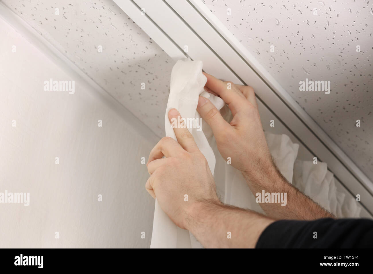 Male hands installing curtains over window Stock Photo