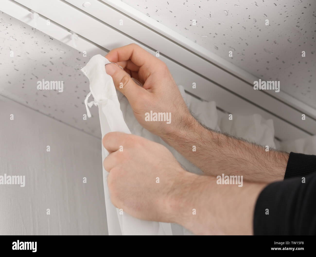 Male hands installing curtains over window Stock Photo