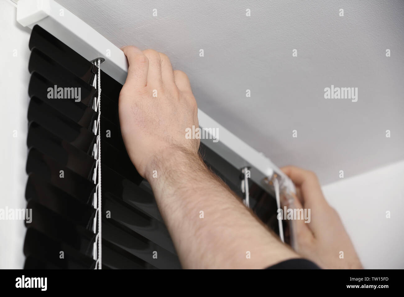 Male hands installing window blinds Stock Photo