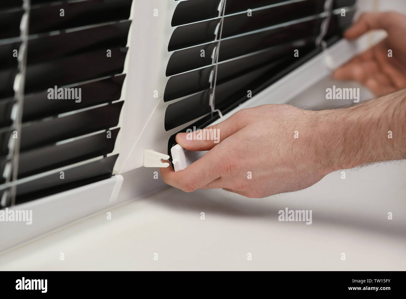 Male hands installing window blinds Stock Photo