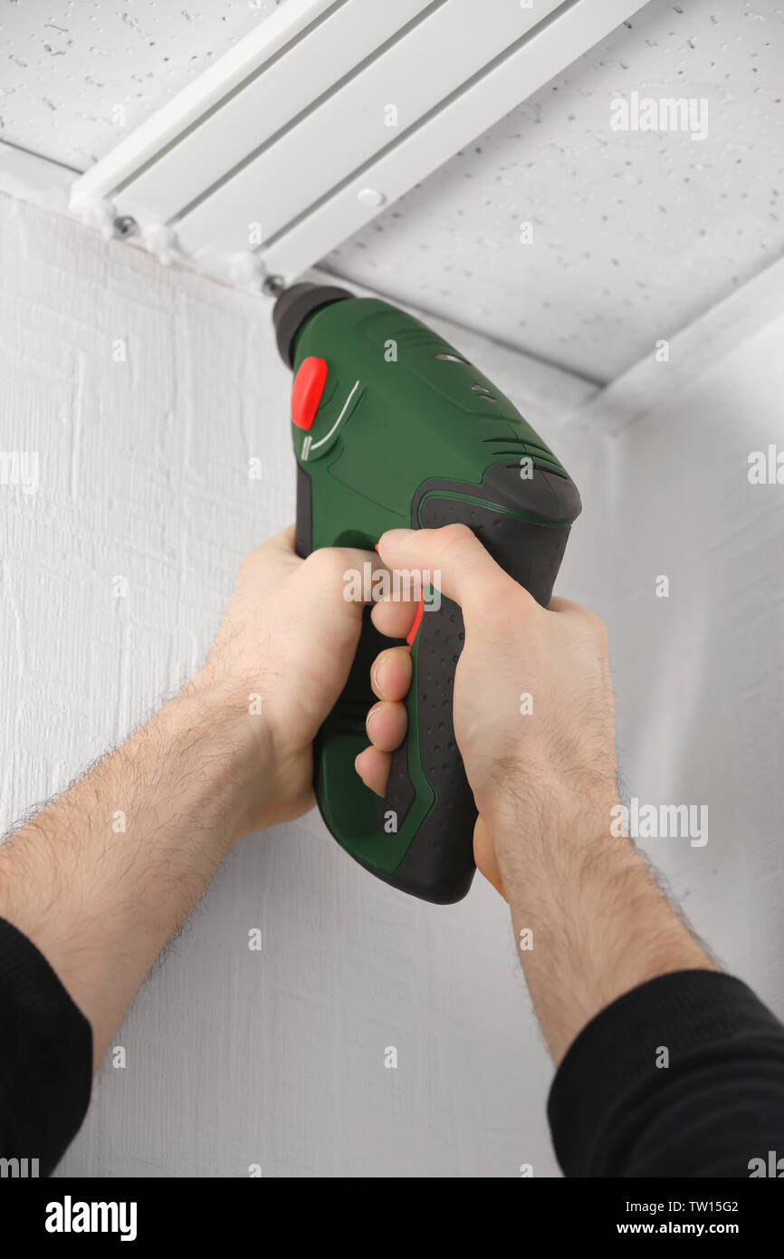 Male hands installing curtain rail using electric screwdriver Stock Photo