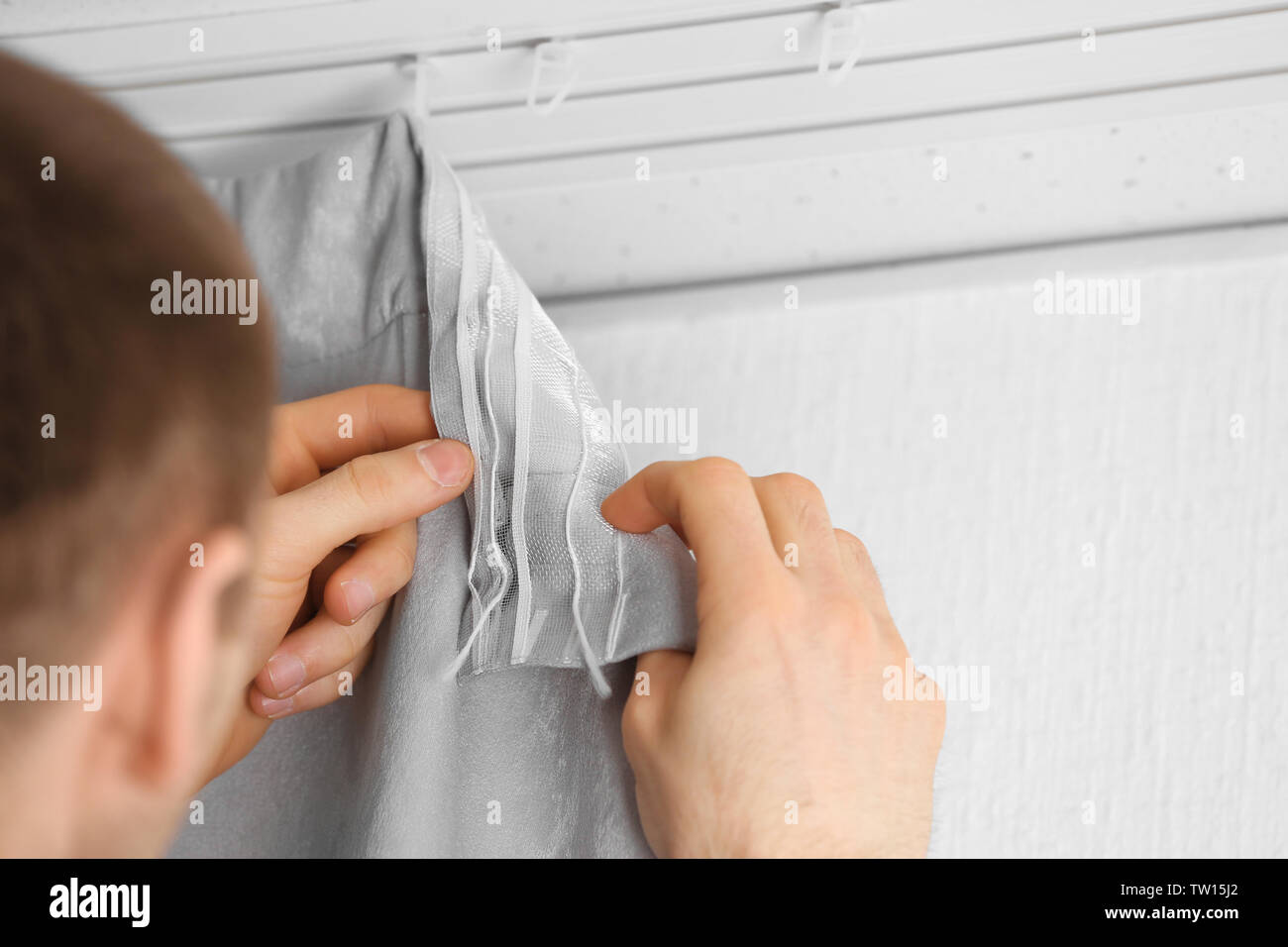 Male hands installing curtains over window Stock Photo