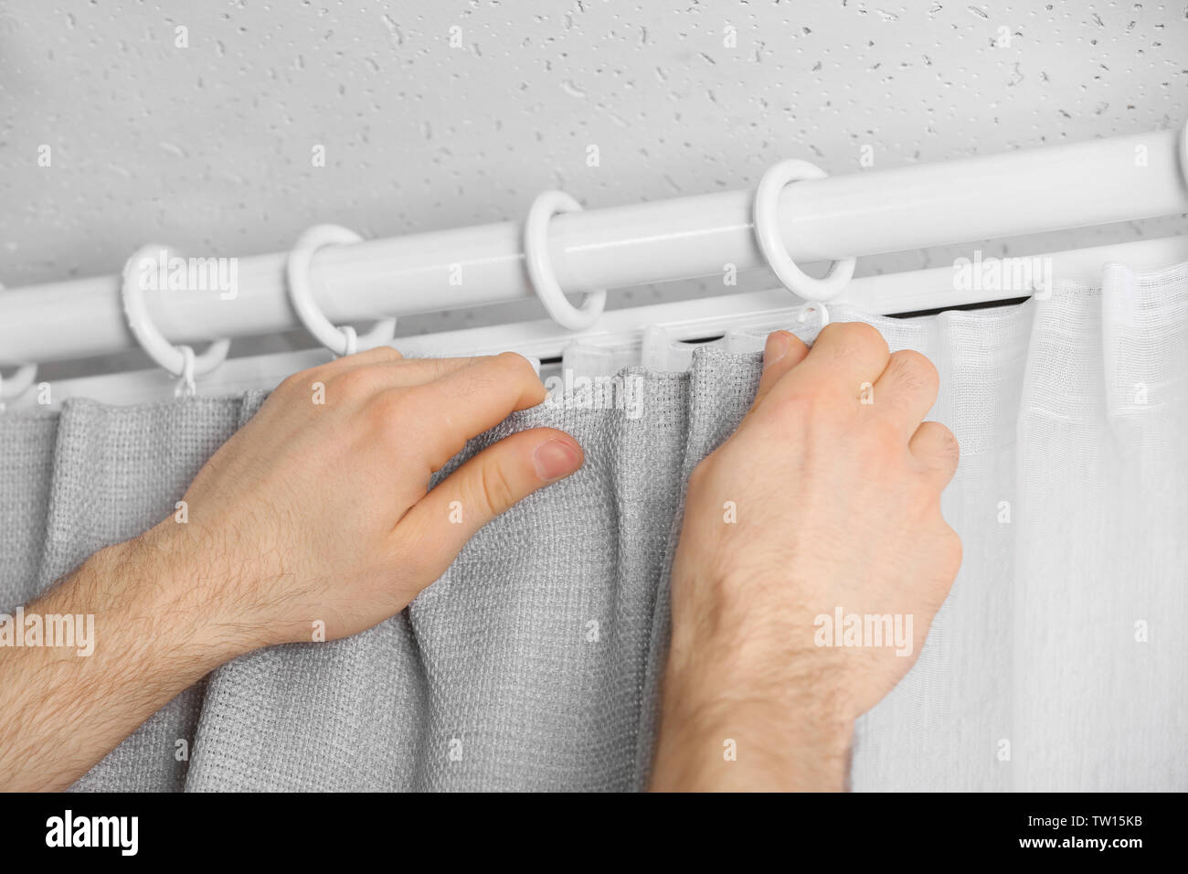 Male hands installing curtains over window Stock Photo