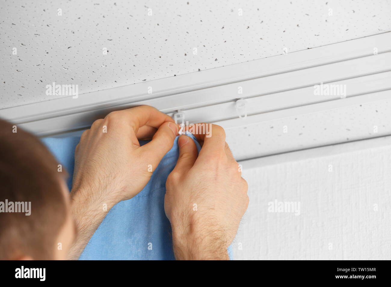 Male hands installing curtains over window Stock Photo