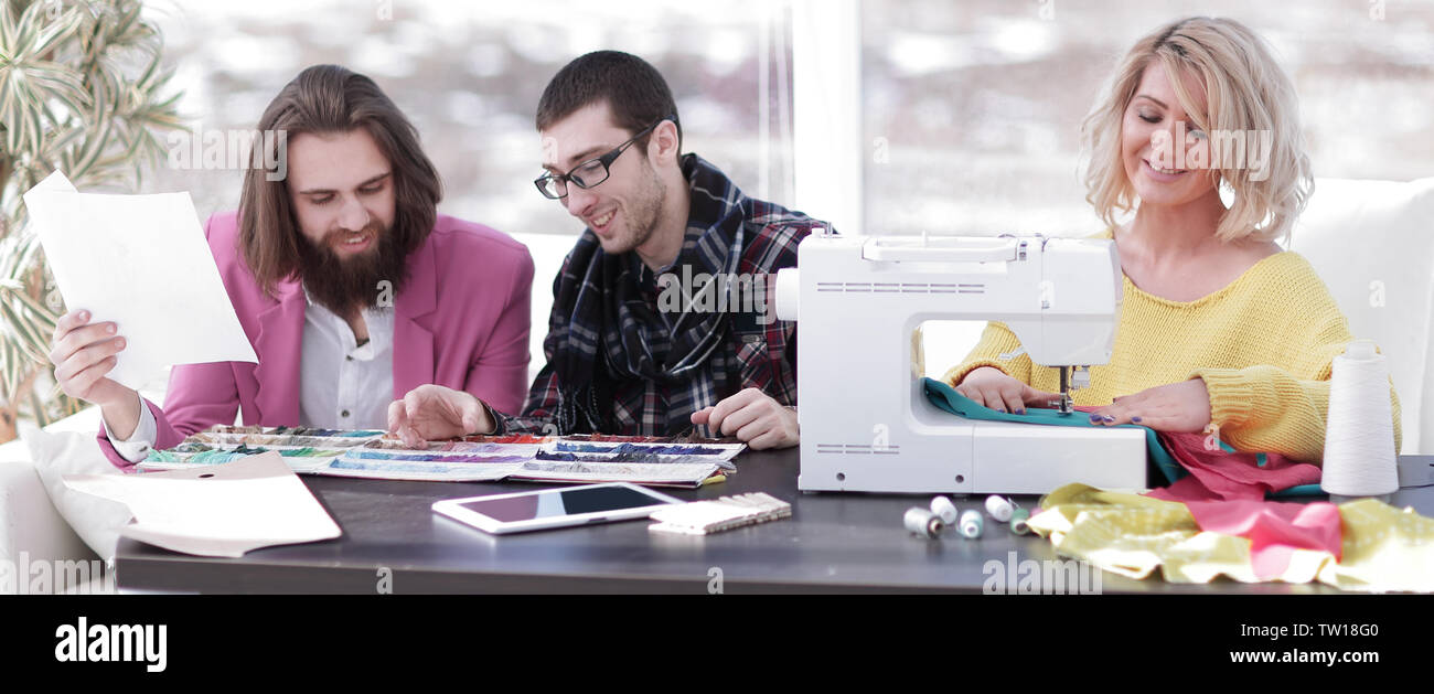 Smiling tailor businesswoman sitting at sewing machine Stock Photo