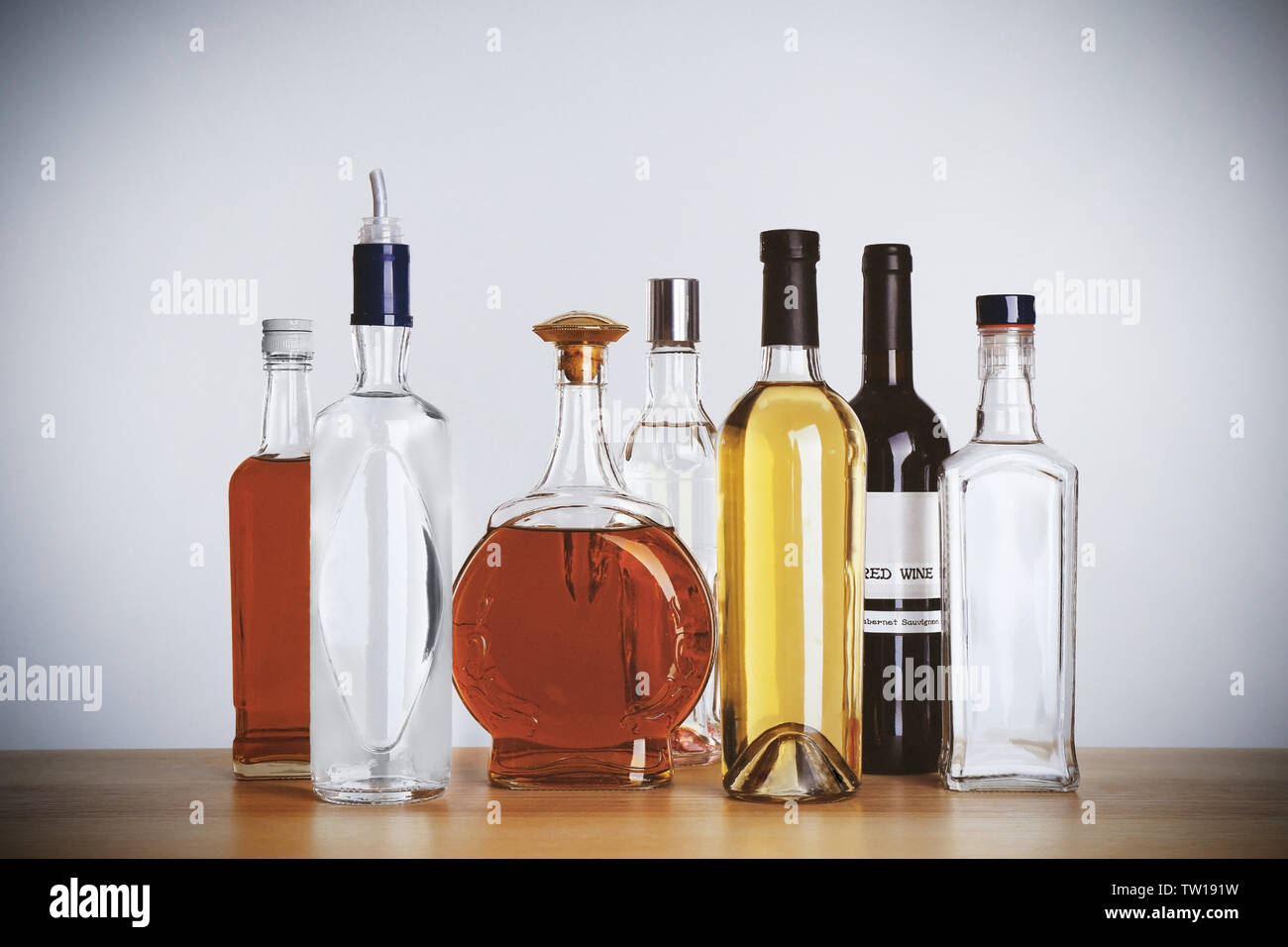 Table with different bottles of wine and spirits on light background Stock Photo