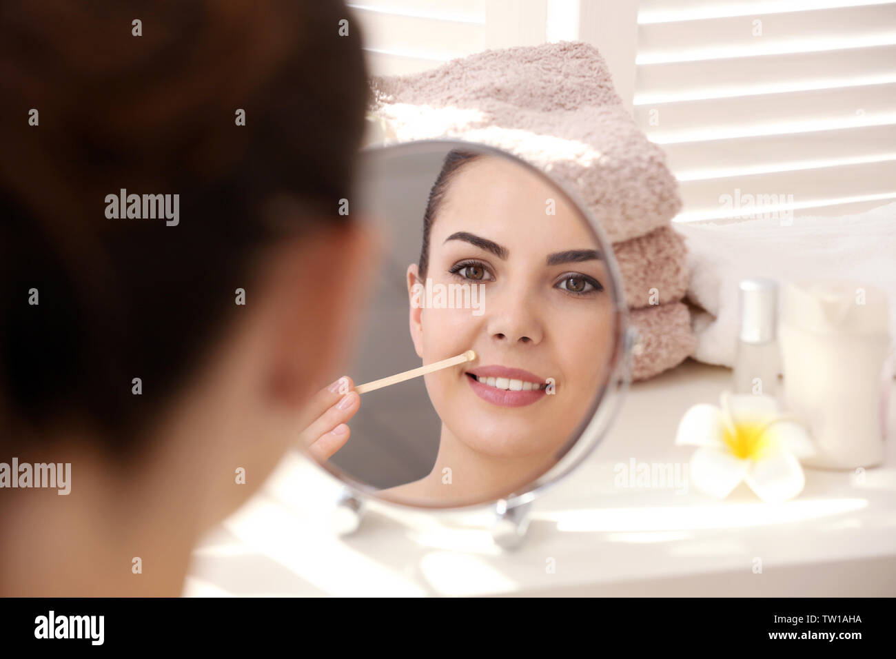 Young Woman Removing Facial Hair With Wax In Front Of Mirror Stock