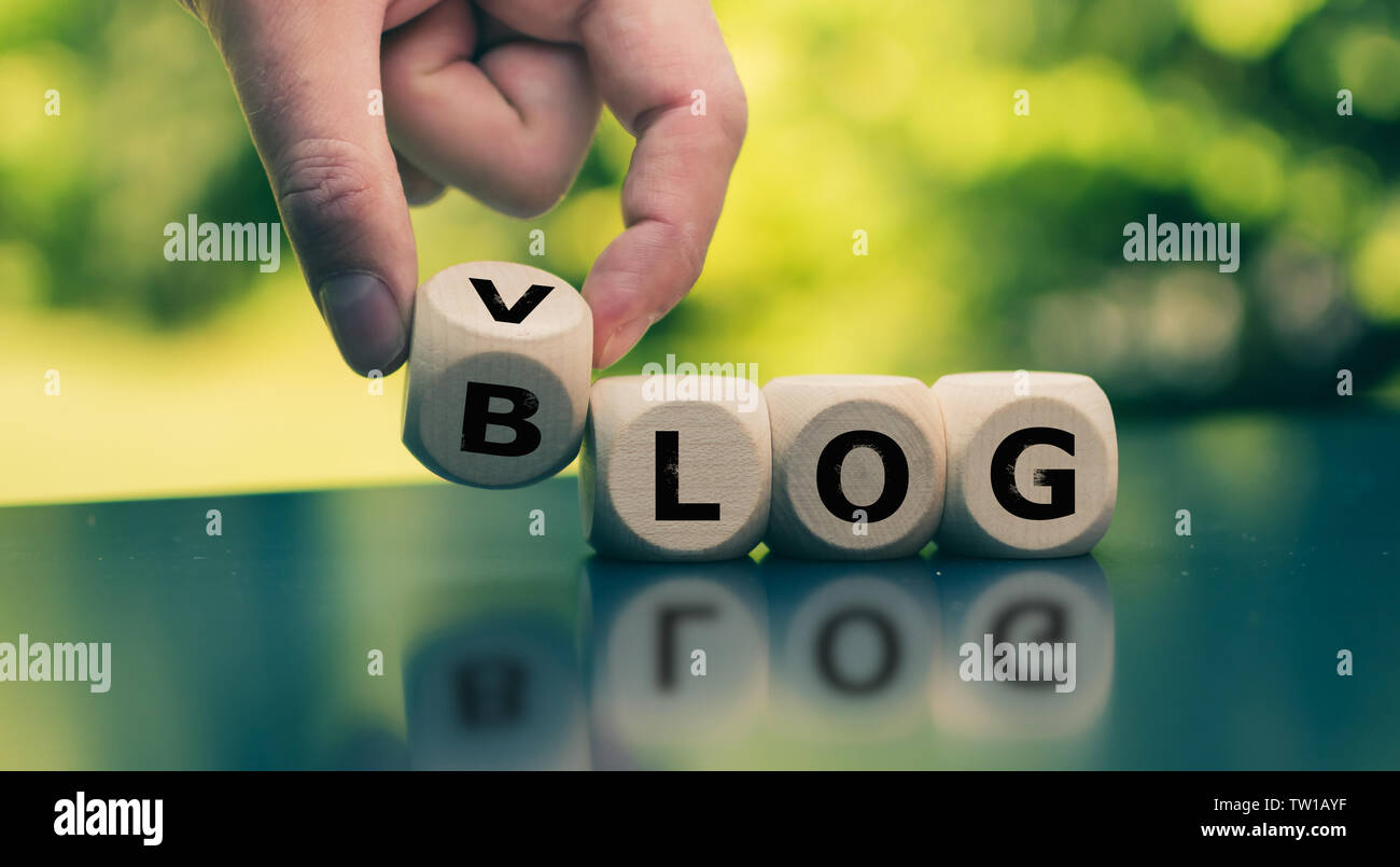 Blog or Vlog? Hand turns a cube and changes the expression 'BLOG' to 'VLOG' (or vice versa). Stock Photo