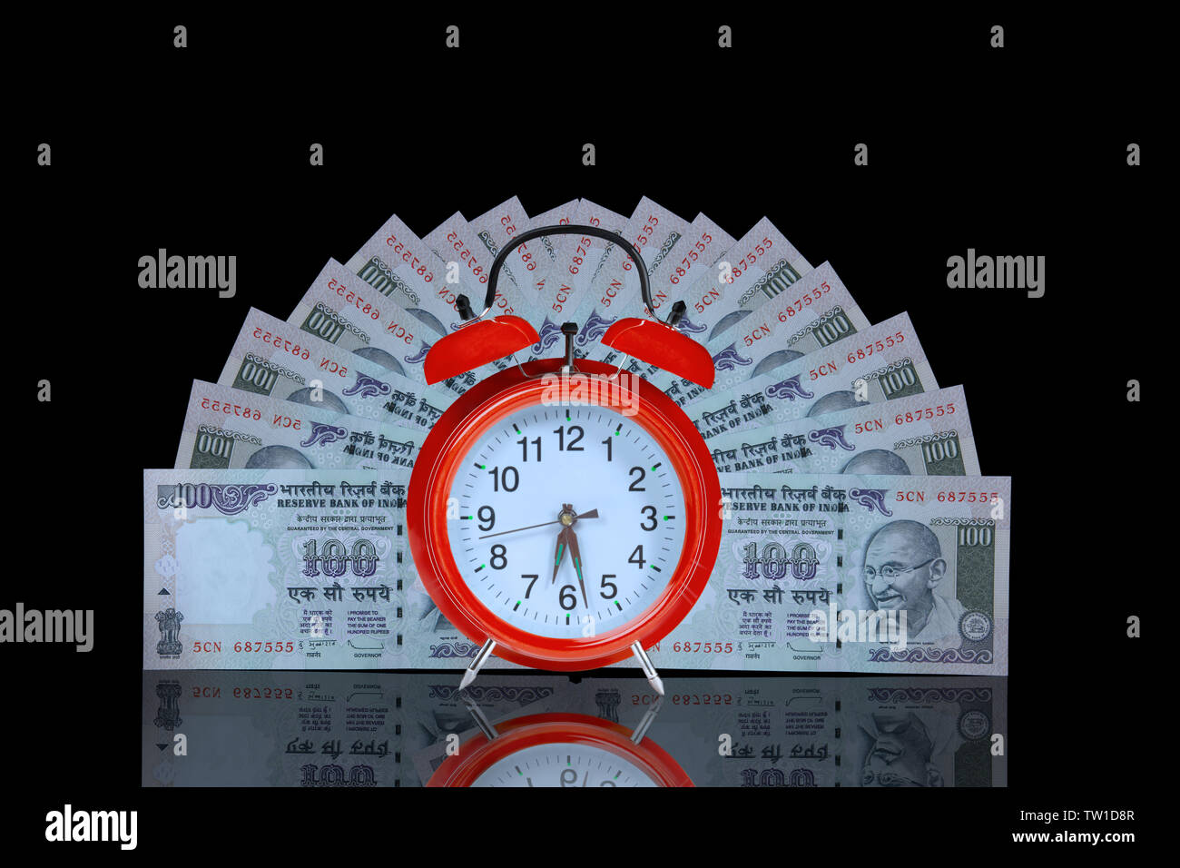 Alarm clock with hundred rupee banknotes Stock Photo