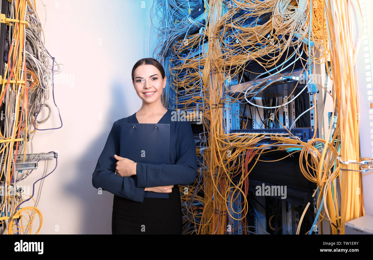 Beautiful young engineer with clipboard in server room Stock Photo