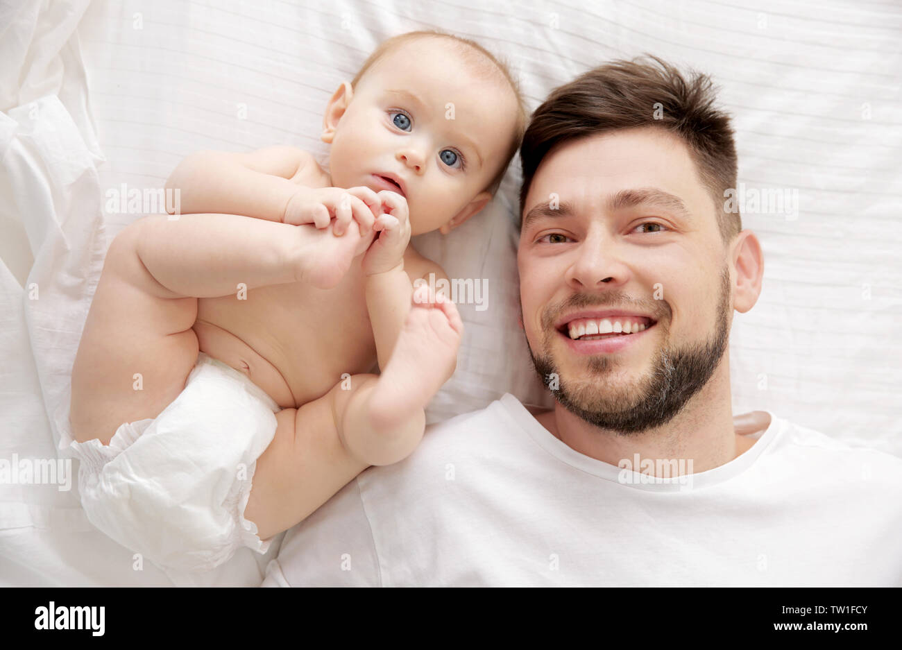 Father lying with cute baby daughter on bed at home Stock Photo - Alamy
