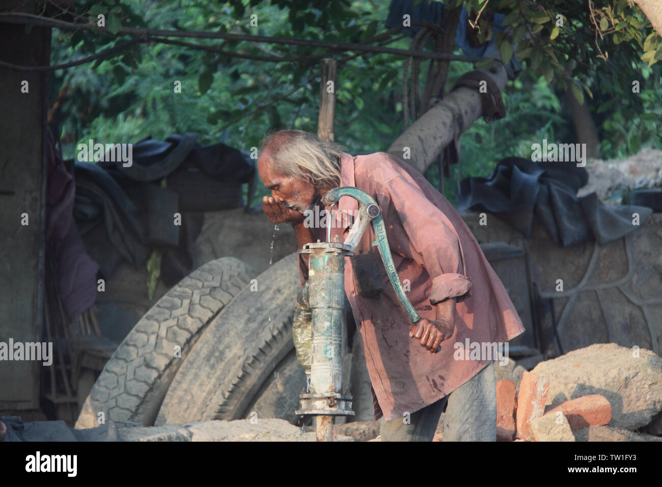 Man drinking water from water pump, India Stock Photo
