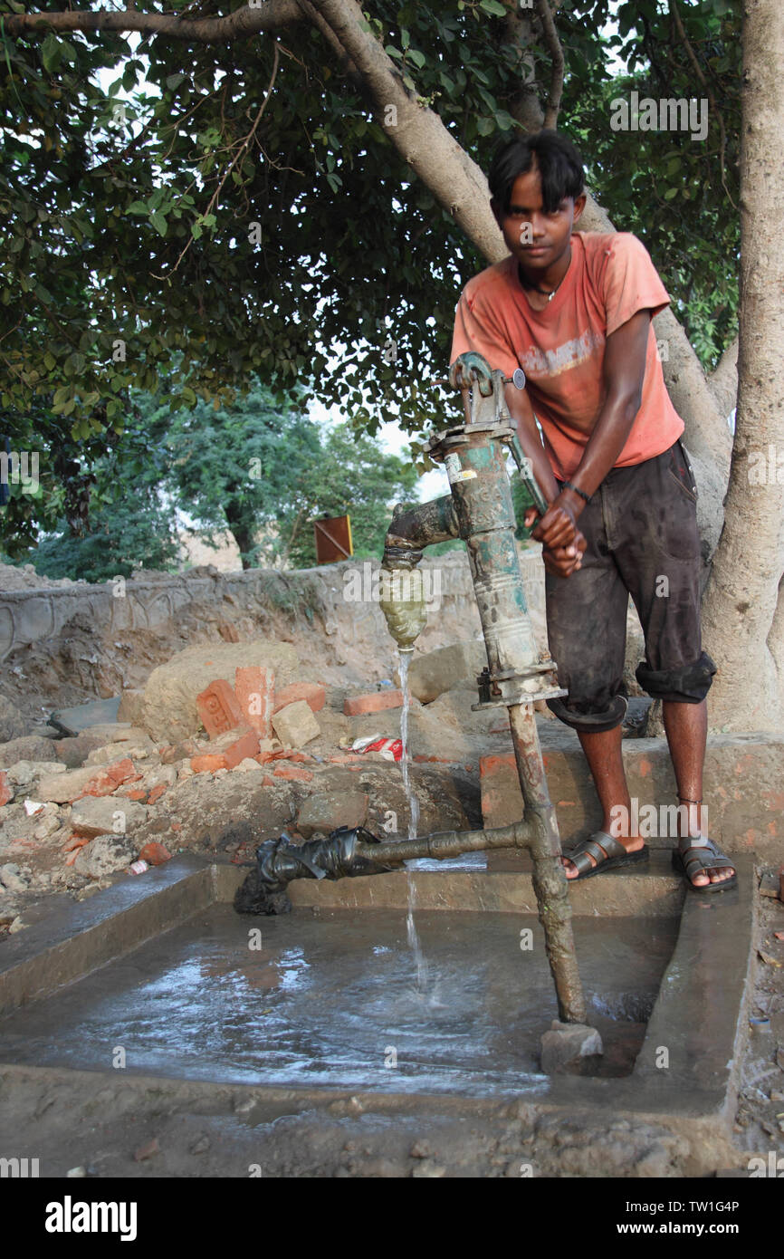Teenage boy holding water pump, India Stock Photo