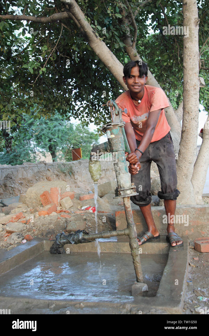 Teenage boy drawing water from water pump, India Stock Photo