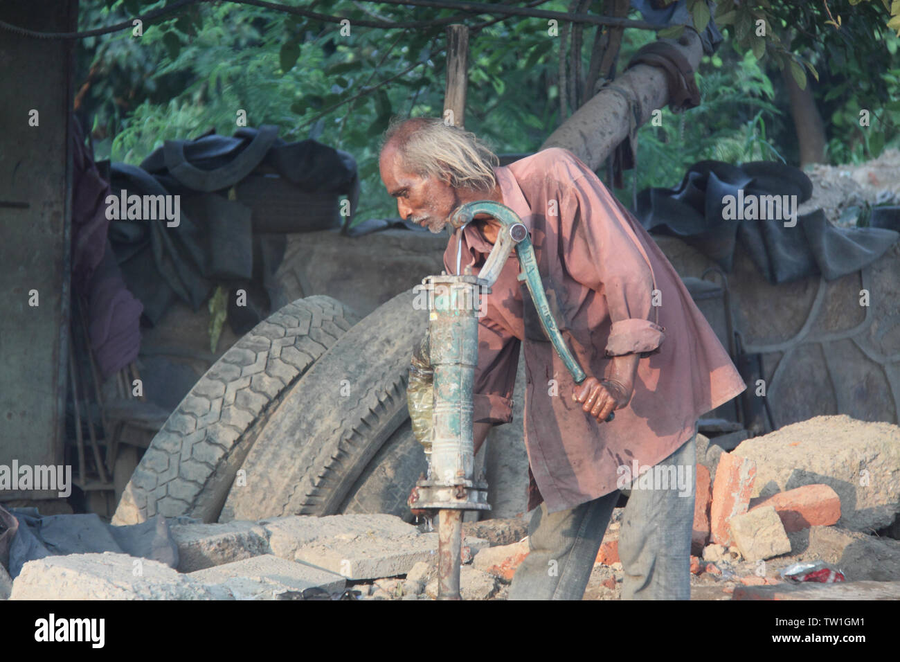 Man drawing water from a water pump, India Stock Photo