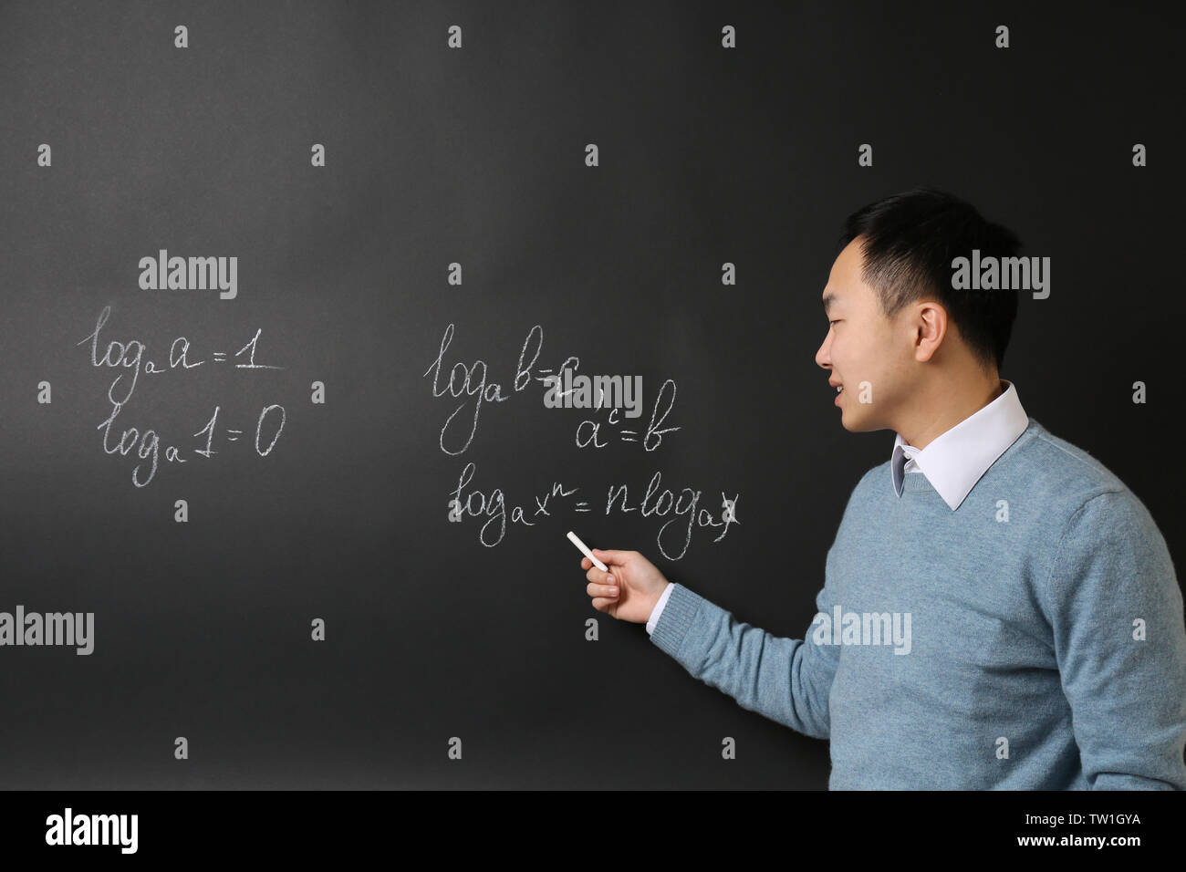 Handsome Asian teacher writing on blackboard Stock Photo