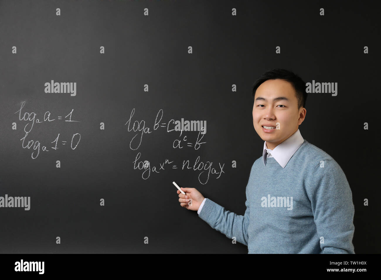 Handsome Asian teacher writing on blackboard Stock Photo
