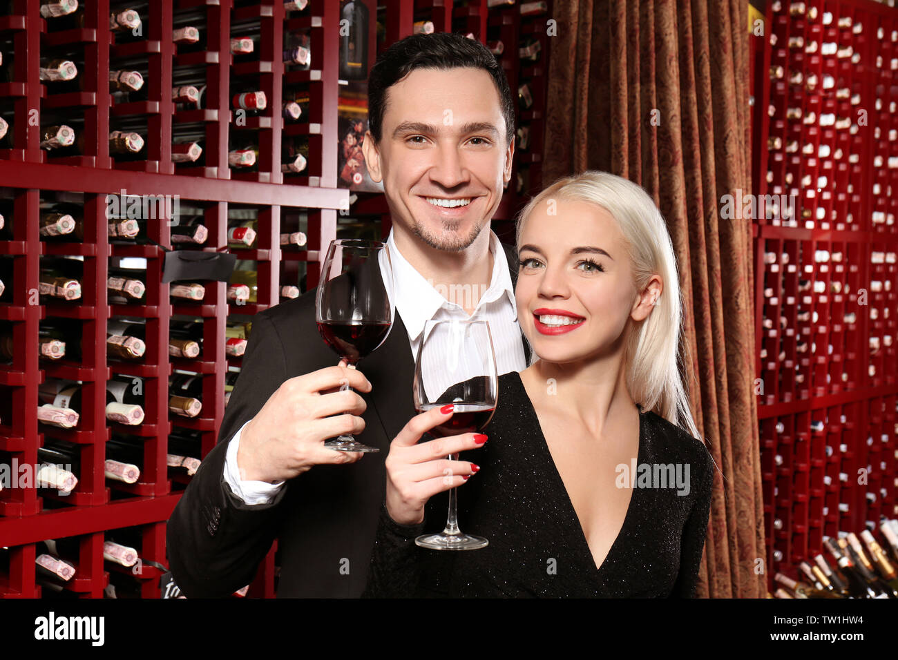 Happy couple drinking in modern wine cellar Stock Photo