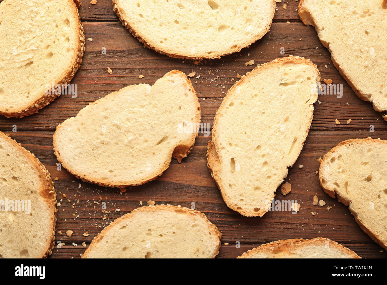 Slices and crumbs of wheaten bread on wooden background Stock Photo