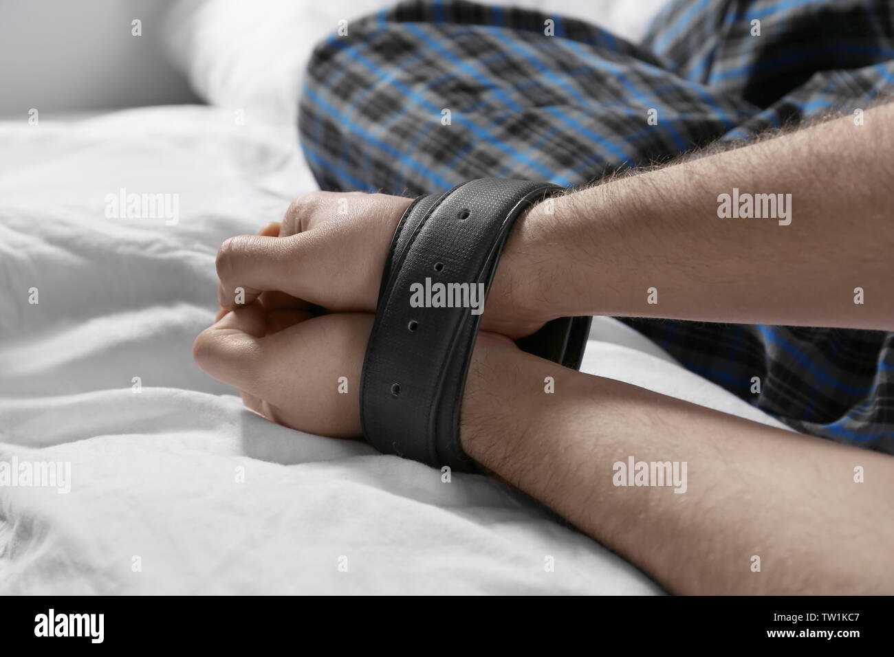 Male hands tied up with belts in bed Stock Photo Alamy