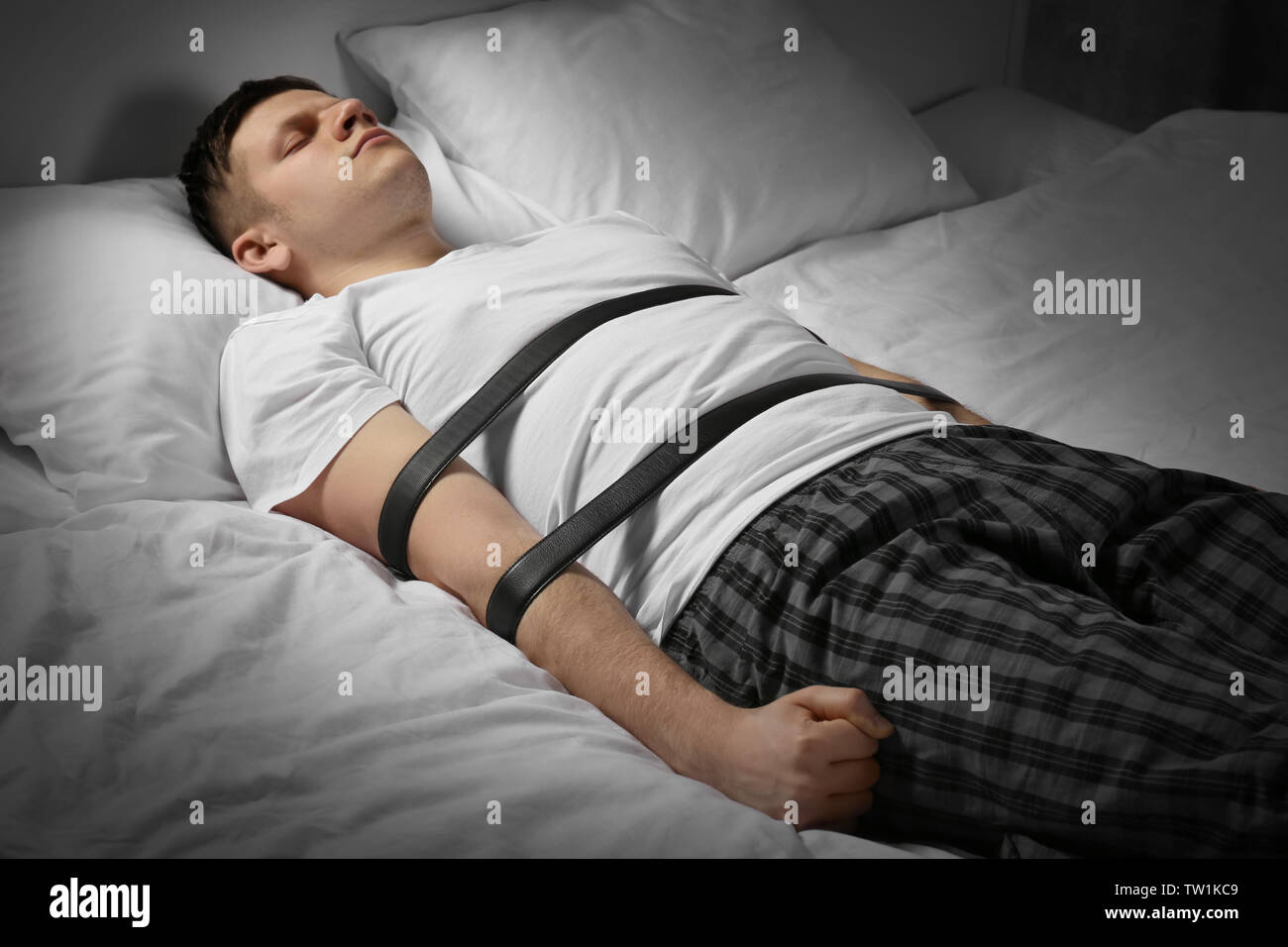 Young man tied up with belts in bed Stock Photo - Alamy.