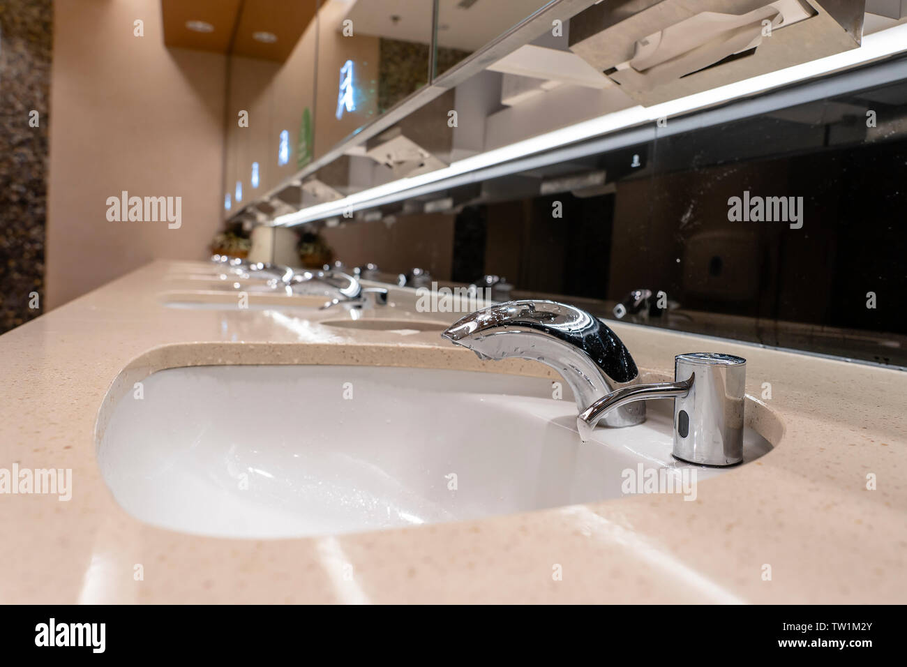 Faucets with washbasin in public restroom, close up. Modern sinks with